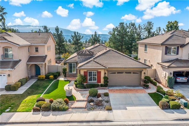 traditional-style house with a mountain view, a garage, driveway, a tiled roof, and a front lawn