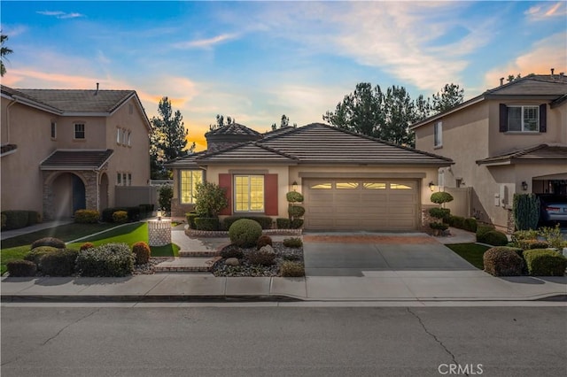 view of front of home with a garage, concrete driveway, a tiled roof, and stucco siding