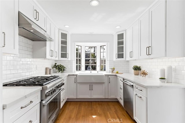 kitchen with stainless steel appliances, white cabinets, a sink, and under cabinet range hood