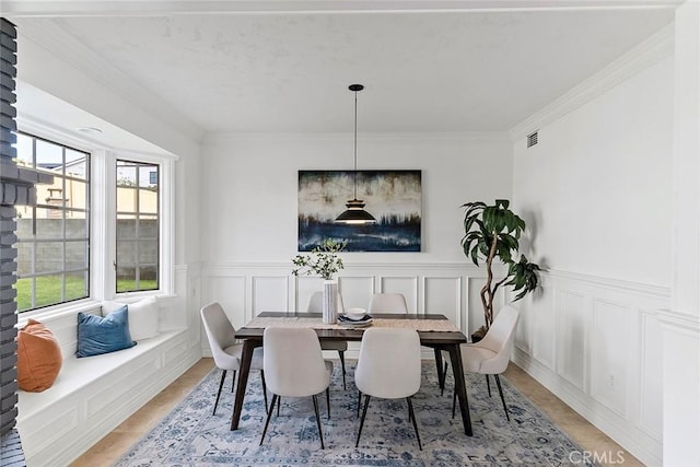 dining room with visible vents, a decorative wall, and crown molding