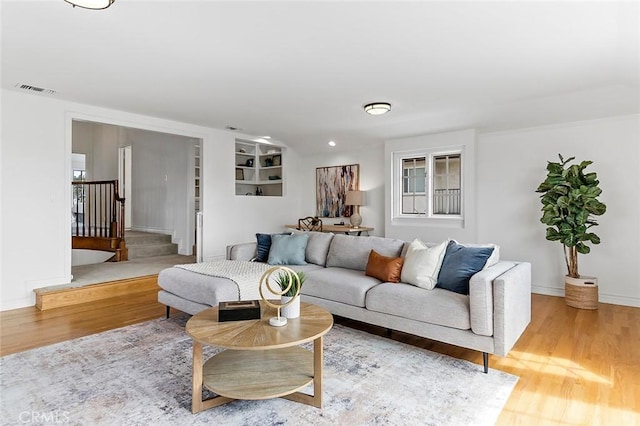 living room with baseboards, visible vents, stairway, and wood finished floors