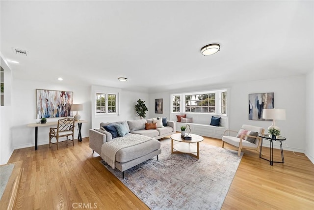 living room with baseboards, visible vents, and light wood finished floors