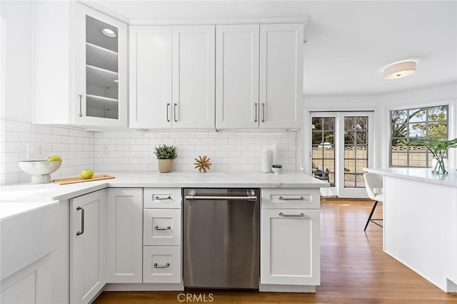 kitchen featuring stainless steel dishwasher, backsplash, wood finished floors, and white cabinets