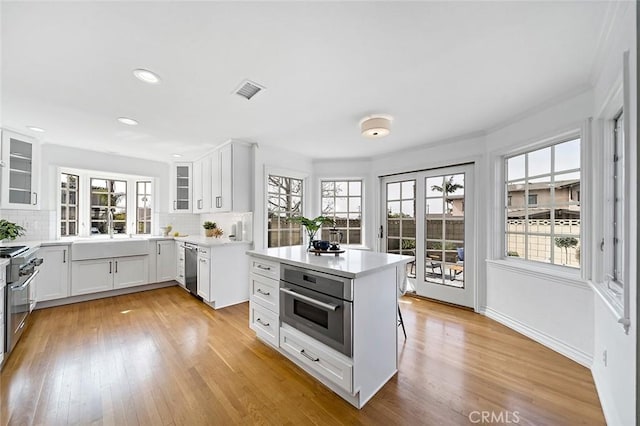 kitchen with appliances with stainless steel finishes, decorative backsplash, a sink, and light countertops