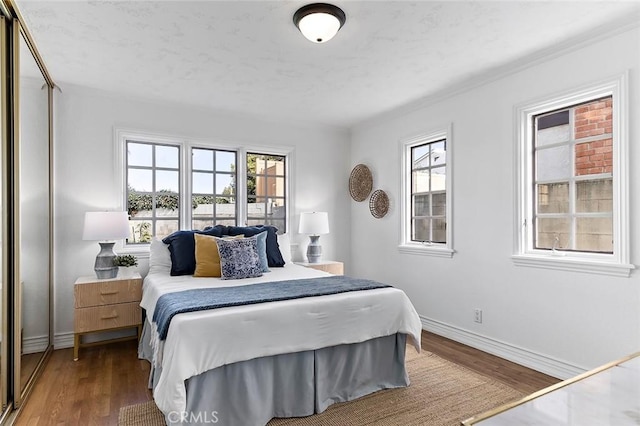 bedroom with multiple windows, baseboards, and wood finished floors