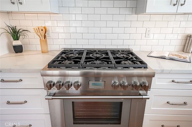 details with light stone counters, high end stainless steel range, backsplash, and white cabinets