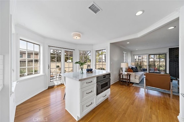 kitchen with light wood-style flooring, visible vents, baseboards, white cabinetry, and light countertops