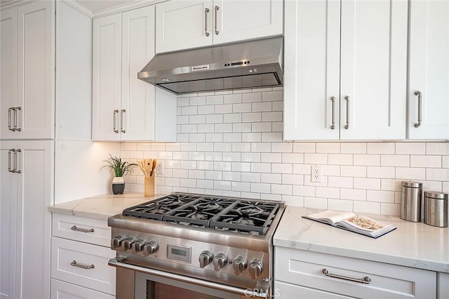 kitchen featuring under cabinet range hood, white cabinetry, high end range, and backsplash