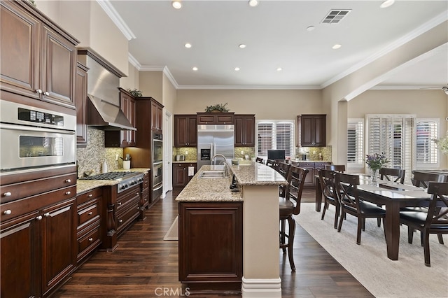 kitchen with visible vents, appliances with stainless steel finishes, a sink, an island with sink, and a kitchen breakfast bar