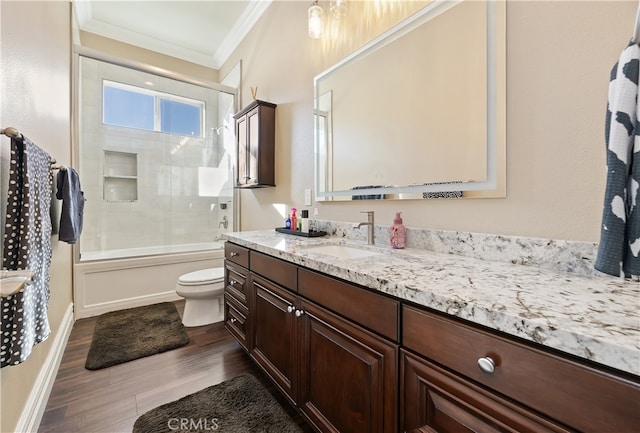 bathroom featuring toilet, ornamental molding, combined bath / shower with glass door, vanity, and wood finished floors