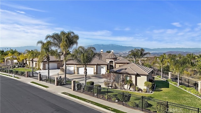 exterior space featuring a mountain view, concrete driveway, a fenced front yard, and a residential view