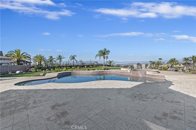 view of pool featuring a patio area, fence, and a pool with connected hot tub