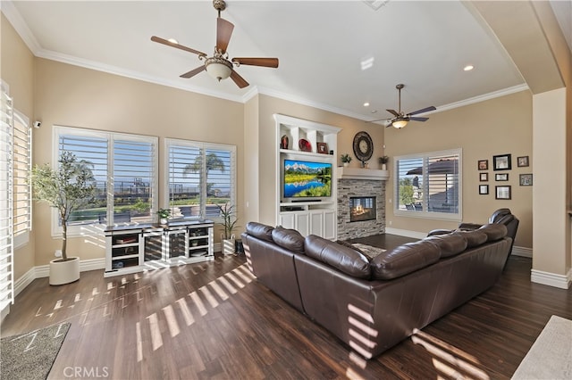 living area with dark wood-style floors, a stone fireplace, crown molding, and baseboards