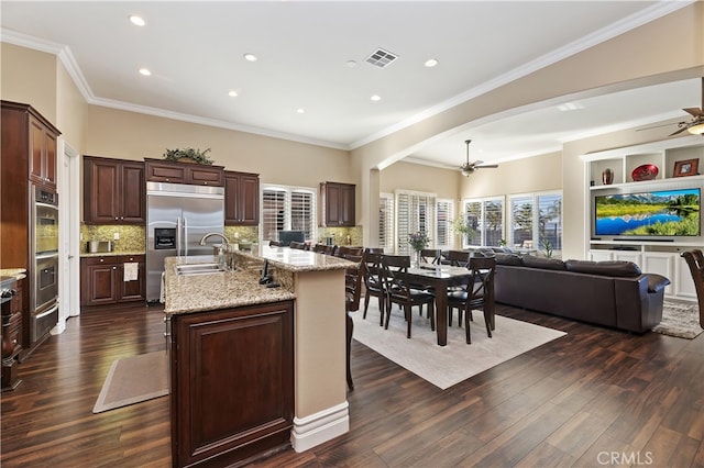 kitchen featuring ceiling fan, a sink, visible vents, open floor plan, and a center island with sink