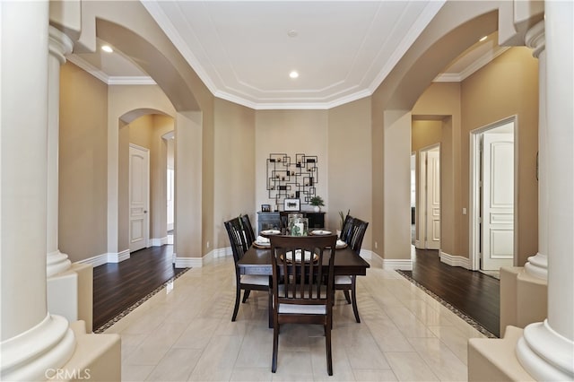 dining area featuring arched walkways, crown molding, decorative columns, and baseboards