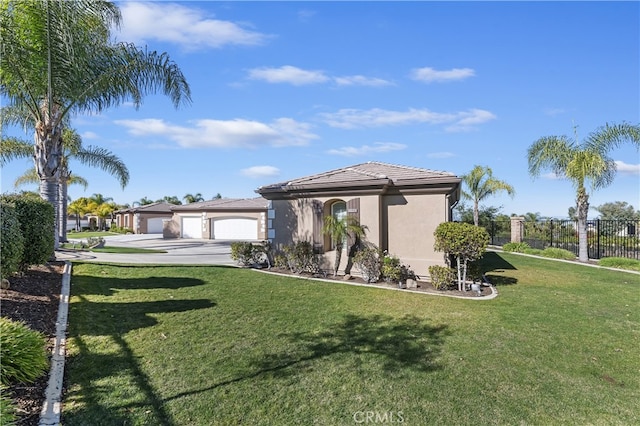 view of front facade featuring concrete driveway, a tiled roof, fence, a front lawn, and stucco siding