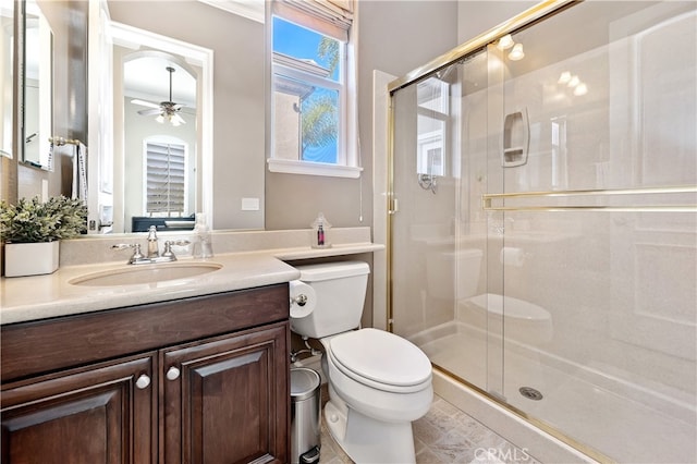 bathroom featuring toilet, a shower stall, ceiling fan, and vanity