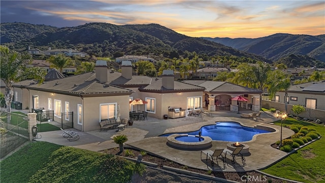 rear view of house featuring a tile roof, a patio, stucco siding, a mountain view, and a fenced backyard