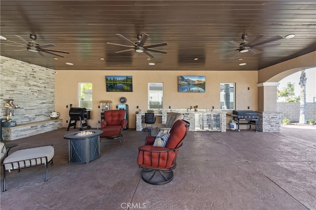 view of patio with ceiling fan, a fire pit, exterior kitchen, and area for grilling