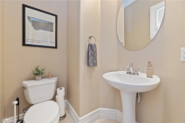 bathroom featuring baseboards, a sink, and toilet