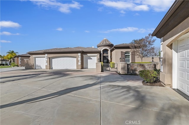 view of front of house featuring an attached garage, fence, concrete driveway, a gate, and stucco siding