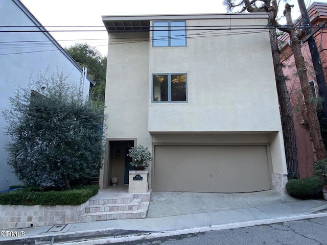 contemporary home with a garage, concrete driveway, and stucco siding