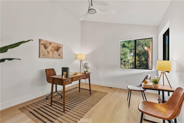 office space with lofted ceiling, light wood-style flooring, baseboards, and ceiling fan