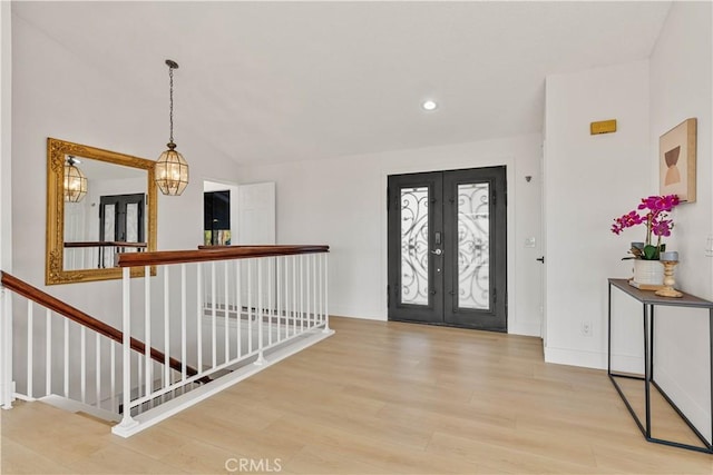 entryway featuring french doors, lofted ceiling, light wood-style flooring, a chandelier, and baseboards