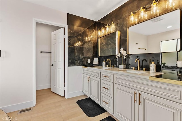 full bathroom featuring double vanity, a sink, visible vents, and wood finished floors