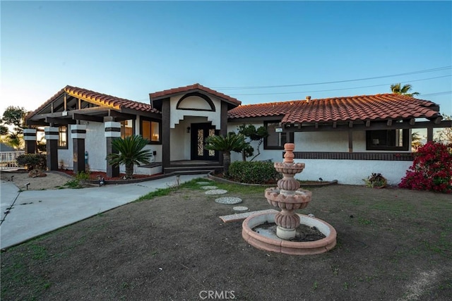 mediterranean / spanish-style home featuring a tiled roof and stucco siding