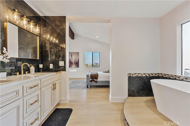 ensuite bathroom featuring double vanity, ensuite bathroom, vaulted ceiling, a sink, and wood finished floors