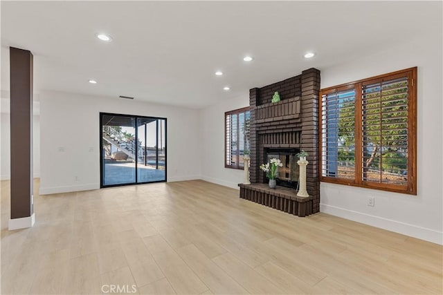 unfurnished living room with baseboards, light wood-type flooring, a brick fireplace, and recessed lighting