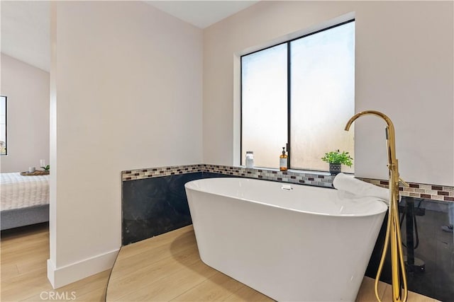 ensuite bathroom featuring wood finished floors, a freestanding bath, and ensuite bathroom