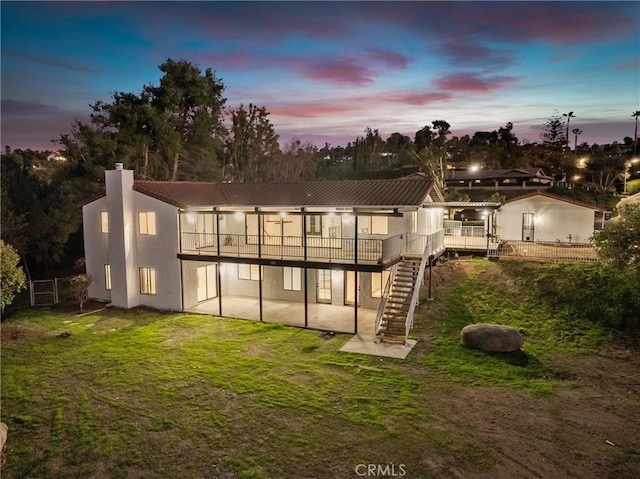 back of property with stairway, a deck, a yard, a patio area, and stucco siding