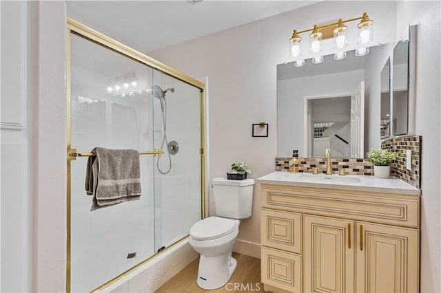 full bath featuring a stall shower, toilet, wood finished floors, vanity, and backsplash