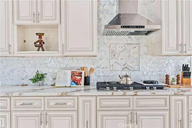 kitchen featuring wall chimney exhaust hood, stainless steel gas cooktop, decorative backsplash, and light stone counters