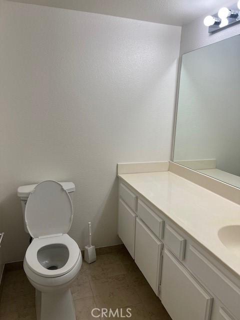 bathroom with toilet, tile patterned flooring, baseboards, and vanity