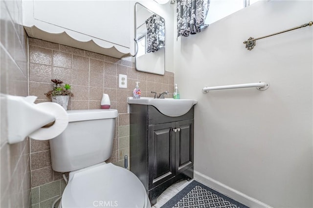 bathroom featuring toilet, baseboards, vanity, and tile walls