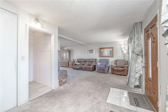 living room with an AC wall unit, a textured ceiling, and light colored carpet