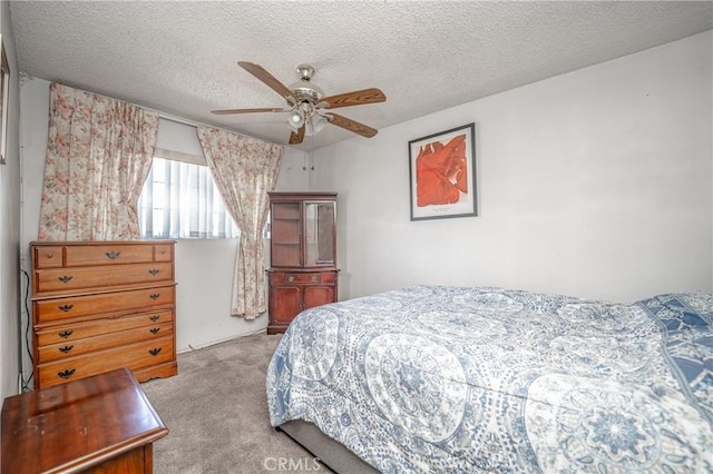 bedroom featuring a ceiling fan, light colored carpet, and a textured ceiling