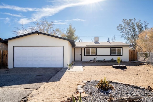 single story home with an attached garage, driveway, fence, and stucco siding