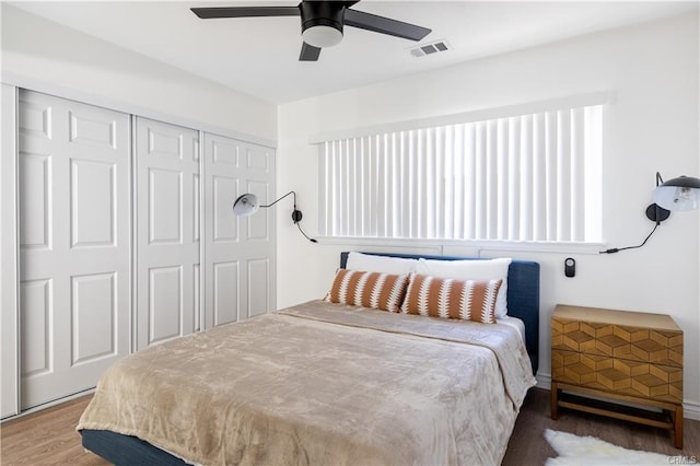 bedroom with a ceiling fan, a closet, visible vents, and wood finished floors