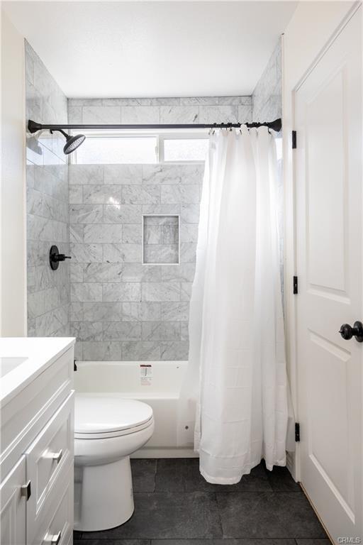 full bath with shower / bathtub combination with curtain, toilet, and vanity