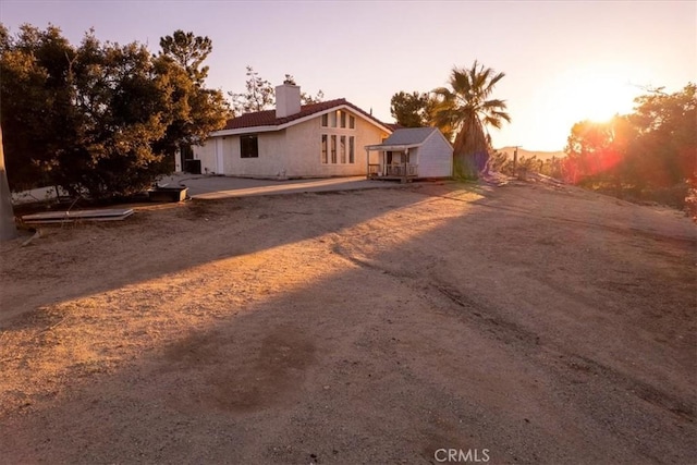 exterior space with dirt driveway and a chimney