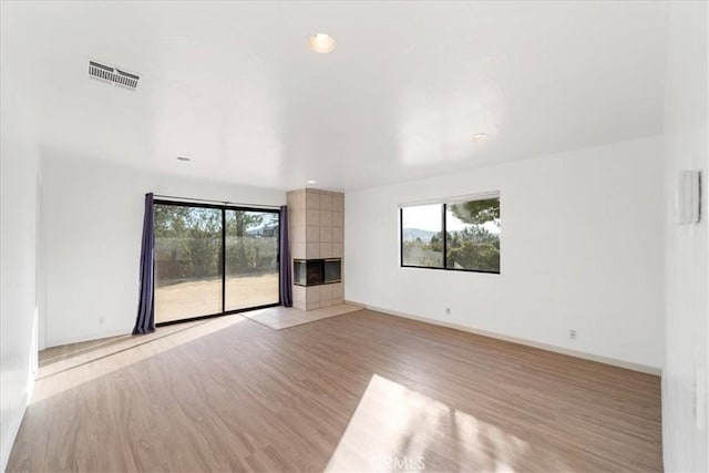 unfurnished living room with baseboards, light wood-style floors, visible vents, and a healthy amount of sunlight