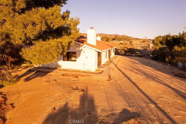 view of side of home with a mountain view and a chimney