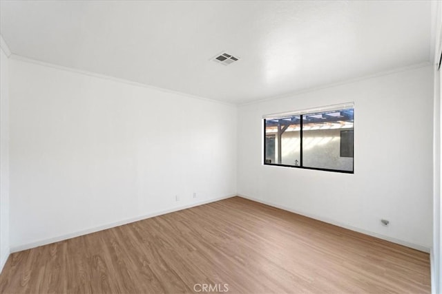 unfurnished room with ornamental molding, light wood finished floors, visible vents, and baseboards