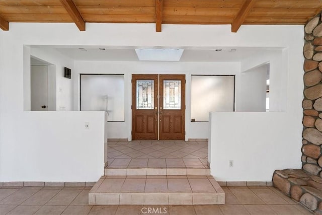 foyer with wood ceiling, light tile patterned flooring, beamed ceiling, and french doors