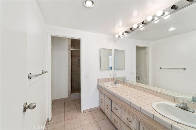 full bathroom featuring double vanity, tile patterned flooring, a sink, and a shower with shower door