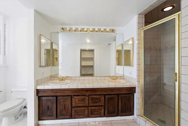 bathroom with toilet, a stall shower, tile patterned flooring, and a sink